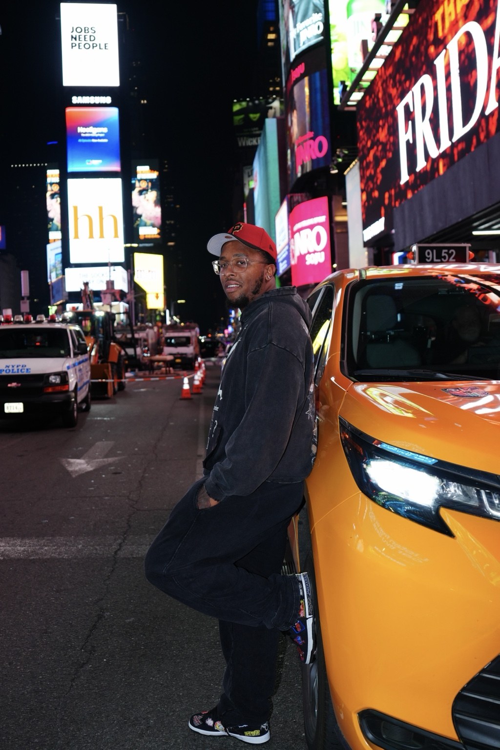 Playground hoodie styled beside a yellow taxi under city lights