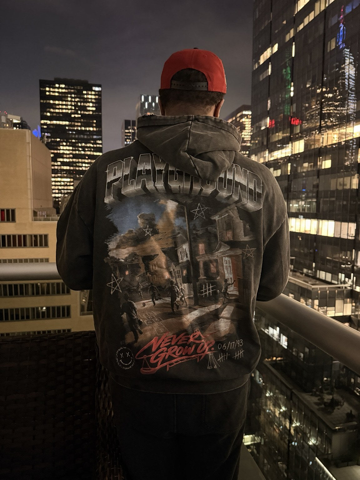 Back of the Playground hoodie against a city skyline at night